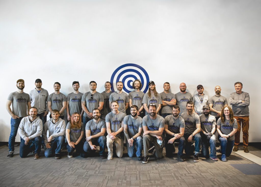 Gruppenfoto des FlackTek-Teams vor einer weißen Wand mit dem blauen FlackTek-Logo
